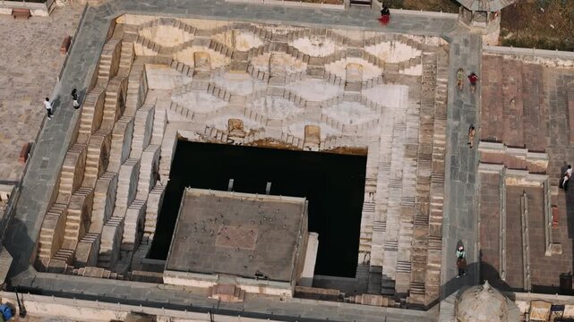 Aerial rotating shot of the panna meena ka kund ancient stepwell in jaipur with tourists visiting the famous landmark