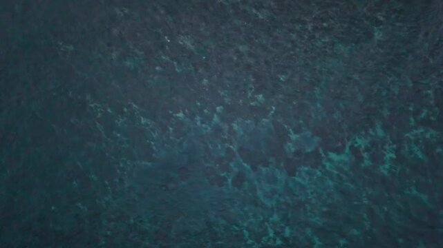 Aerial view of Amed Beach showing clear turquoise water and coral reef patterns in Bali, Indonesia.