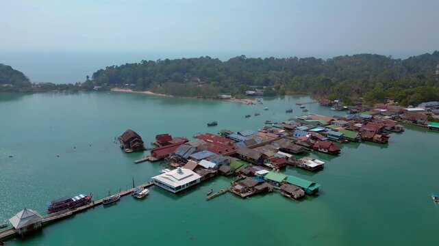 Coastal community living in houses on stilts over calm blue water, surrounded by lush green islands, representing traditional life. Wonderful aerial view drone shot panorama from above