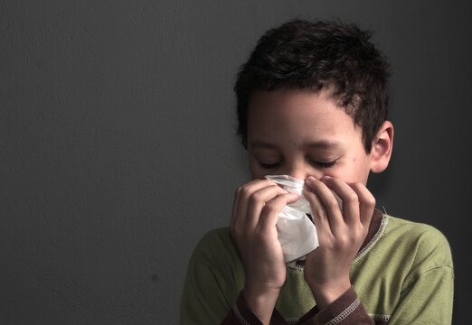 flu epidemic with child blowing nose after catching a cold with people on dark background stock image stock photo