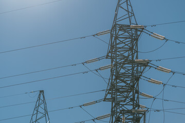 Highvoltage transmission tower stands tall against a clear blue sky during the day © beholdereye
