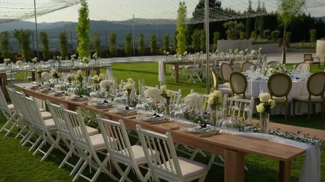 Garden reception with white roses folding chairs and string lights over hillside view
