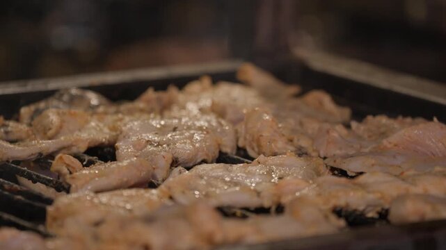 Seasoned poultry sizzling over charcoal grill bars at an outdoor barbecue