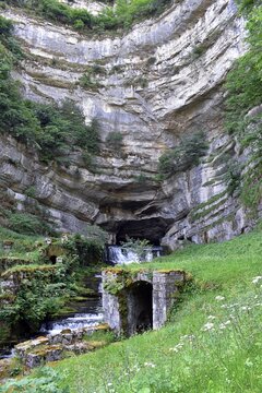 Source de la Loue jaillissant d'une caverne sous une falaise, Ouhans, France.