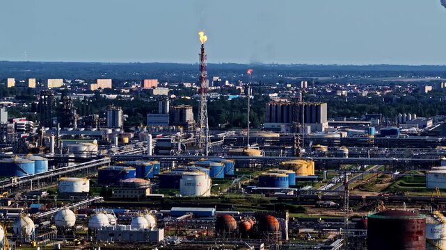 Aerial view of the ORLEN Plock Production Plant featuring industrial storage tanks, complex pipeline networks, and a tall flare stack in Plock, Mazowieckie, Poland.