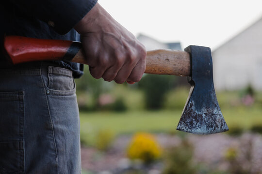 Close-up of a man holding an axe outdoors, creating a dark crime scene concept associated with violence, threat, aggression and criminal danger.