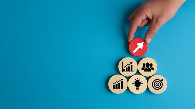 A hand placing a red wooden circle with an upward arrow on a pyramid of representing business growth, teamwork, and strategic development