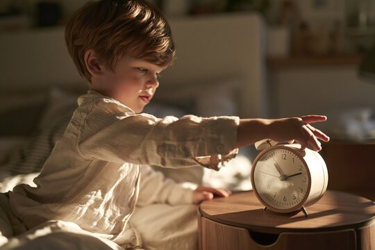 Child Adjusting Alarm Clock in Bed