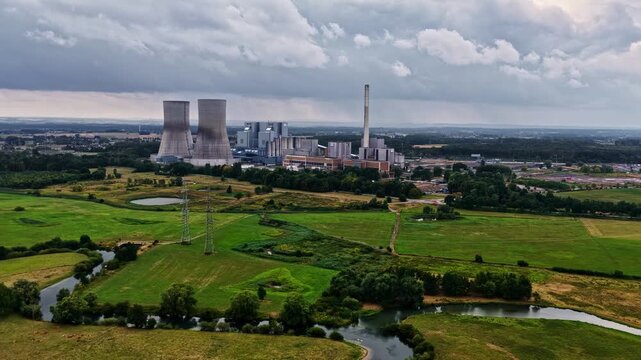 Aerial view of RWE Westfalen power plant with cooling towers and industrial buildings surrounded by green fields and a river in Hamm, Nordrhein-Westfalen, Germany.
