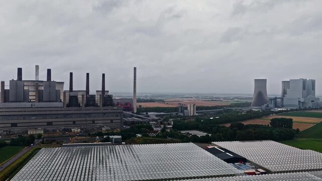 Aerial view of RWE Power AG Kraftwerk Neurath with its large cooling towers and industrial chimneys rising above the surrounding greenhouses and fields in Grevenbroich, Nordrhein-Westfalen, Germany.