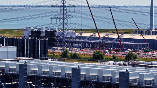 Aerial view of the Google Data Center construction site featuring rows of cooling units, heavy cranes, and power lines in Eemshaven, Groningen, Netherlands.