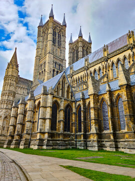 View of Lincoln Cathedral featuring intricate gothic architecture, stone walls, and stained glass windows under a blue sky in Lincoln, England, United Kingdom.