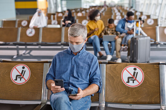Travelers maintain distance in a public waiting area, adhering to safety protocols during a health crisis