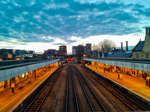 View of Lincoln railway station platforms with tracks leading into the distance under a dramatic cloudy sky at dusk in Lincoln, England, United Kingdom.