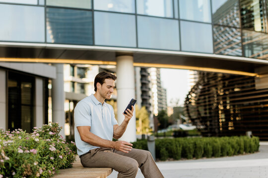 Man smiles while using smartphone in a modern urban setting