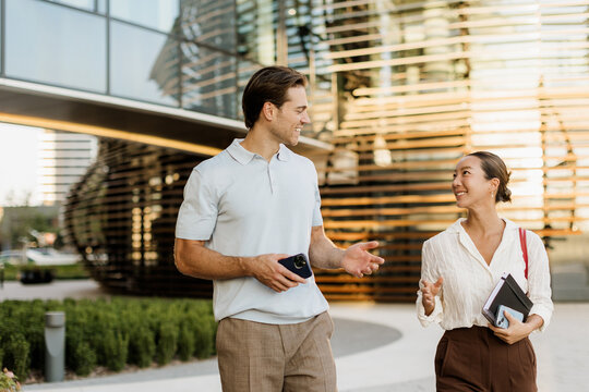 Korean woman and Caucasian man enjoy a sunny day while walking and chatting
