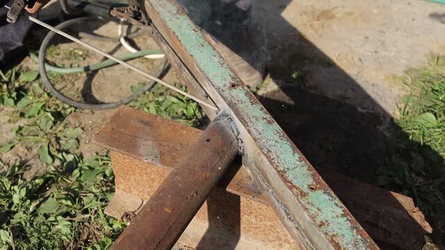 Welding metal in a sunny outdoor workshop