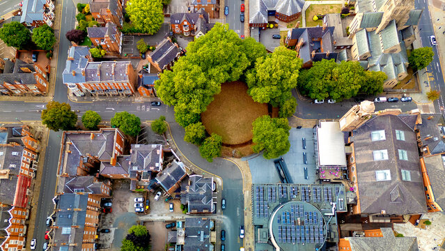 Direct top down aerial shot of round green park surrounded by streets
