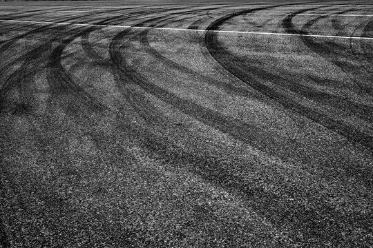 Dark Tire Tracks Burning Rubber on Road or Street with Painted Lines Showing Traffic Flow Peeling Out with Car Skid Marks