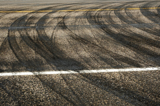 Dark Tire Tracks Burning Rubber on Road or Street with Painted Lines Showing Traffic Flow Peeling Out with Car Skid Marks