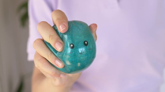 Hand squeezes blue dumpling squishy toy, showing soft texture, flexible shape and glossy surface. Close product demonstration highlights tactile play, stress relief and sensory stimulation.
