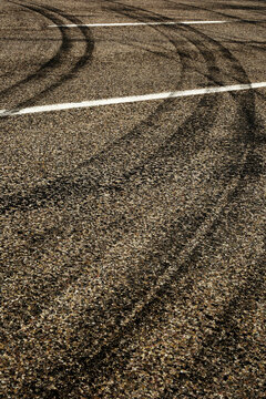 Dark Tire Tracks Burning Rubber on Road or Street with Painted Lines Showing Traffic Flow Peeling Out with Car Skid Marks