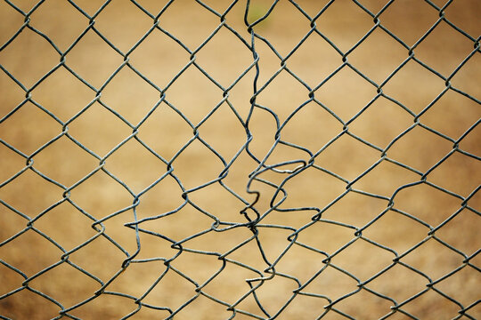 Old Broken and Bent Chain Link Fence Stretched and Strained Metal Fencing