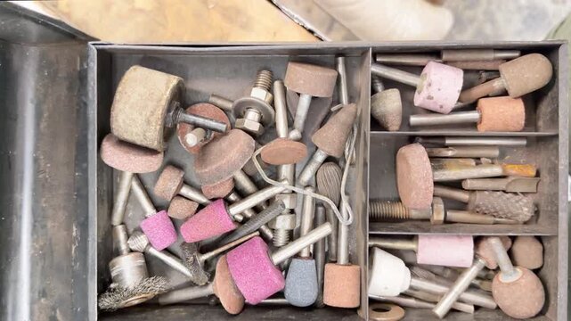 Workshop toolbox with assorted rotary tools, grinding bits, grinding stones, abrasive bits used for metal working and wood.