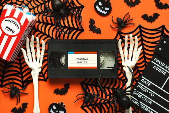 Top view of VHS video tape cassette with the text horror movies alongside Halloween popcorn, clapperboard and Halloween party decoration. Halloween movies concept