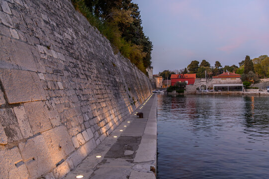 Illuminated walkway along the Venetian city walls at the Fosa harbor at dusk, Zadar, Croatia