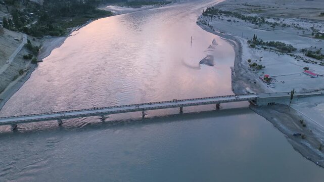 Vehicles crossing Chumik Bridge over the Indus River at sunset, showing sunset colors in the murky water in Skardu Gilgit-Baltistan region