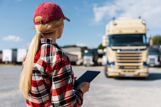Woman truck driver with tablet checking logistics in a parking lot