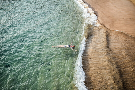 top view of woman floating in the sea near sandy beach