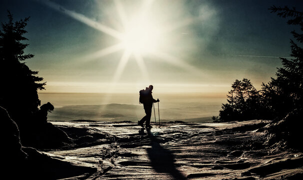 Backcountry skier reaching the summit at sunset