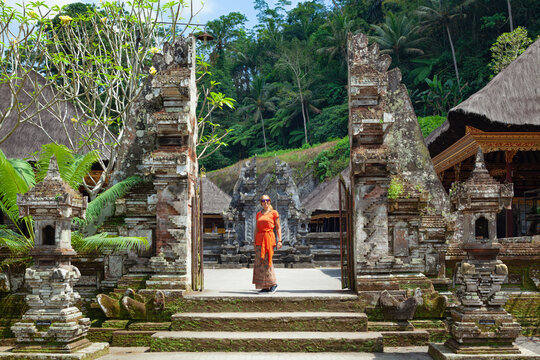 Young woman in traditional sarong at temple entrance gate Candi Bentar in  Gunung Kawi, Bali. Popular tourist place for day tour in Ubud location. Family travel lifestyle in Indonesia