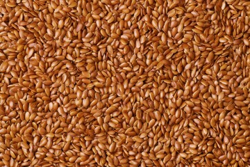 Fototapeta premium Brown flaxseeds spread out on a flat surface, showing the texture and color of the seeds