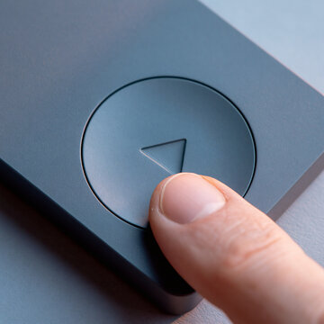 Ai generated close-up finger pressing circular play button on smooth device with interface, triangle