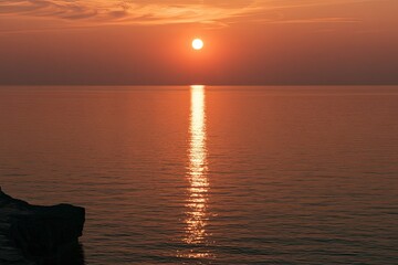 Obraz premium Fiery sun descends over calm ocean, casting golden reflection