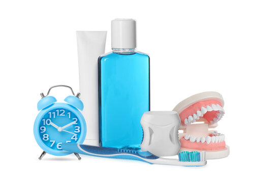 Dental care products, alarm clock and model of jaw isolated on white. Oral hygiene routine