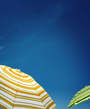 Striped sun umbrellas against blue sky. Summer season
