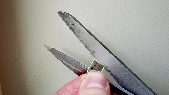 Scissors Cutting a Sim Card in Half Data Security Concept