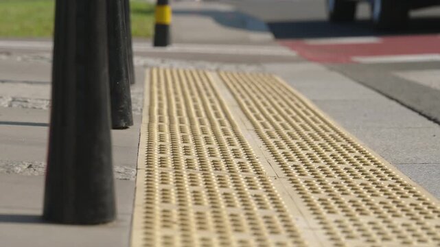 Ground level close up of woman walking across an urban pedestrian crossing in black leggings and pink sandals, female feet stepping over tactile paving on sunny summer day in modern city