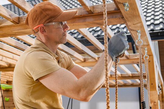 Carpenter tightening swing hardware on a wooden beam