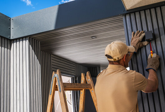 Worker installing an outdoor wall light with a screwdriver