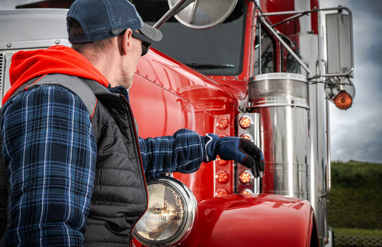 Truck driver beside the cab and headlight of a semi truck