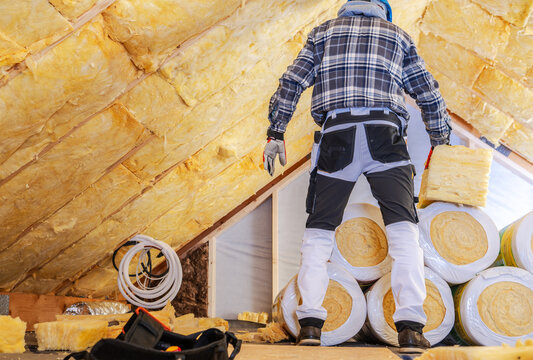 Builder carrying insulation inside an attic under renovation