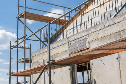 Scaffolding and exposed rebar on an unfinished house exterior