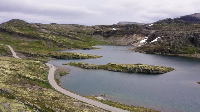 Car driving throught Norvegian severe Tundra nature with birdsyey top view Picturesque northern lakes Norwagian landscape and modern highway construction aerial 4K video. Rondane National Park, Norway