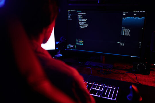 Person coding software on computer at night