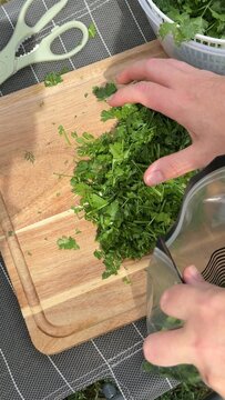 Freshly chopped herbs on a wooden cutting board suggest culinary preparation; ideal for cooking or garnishing dishes; embodies a fresh and vibrant kitchen feeling